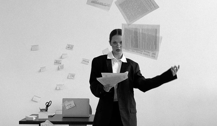 A woman tossing papers into the air in a studio